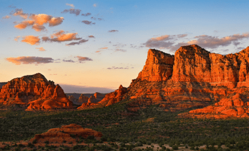 Sunset lights towering red sandstone cliffs and mesas in a desert canyon with orange-hued rock.
