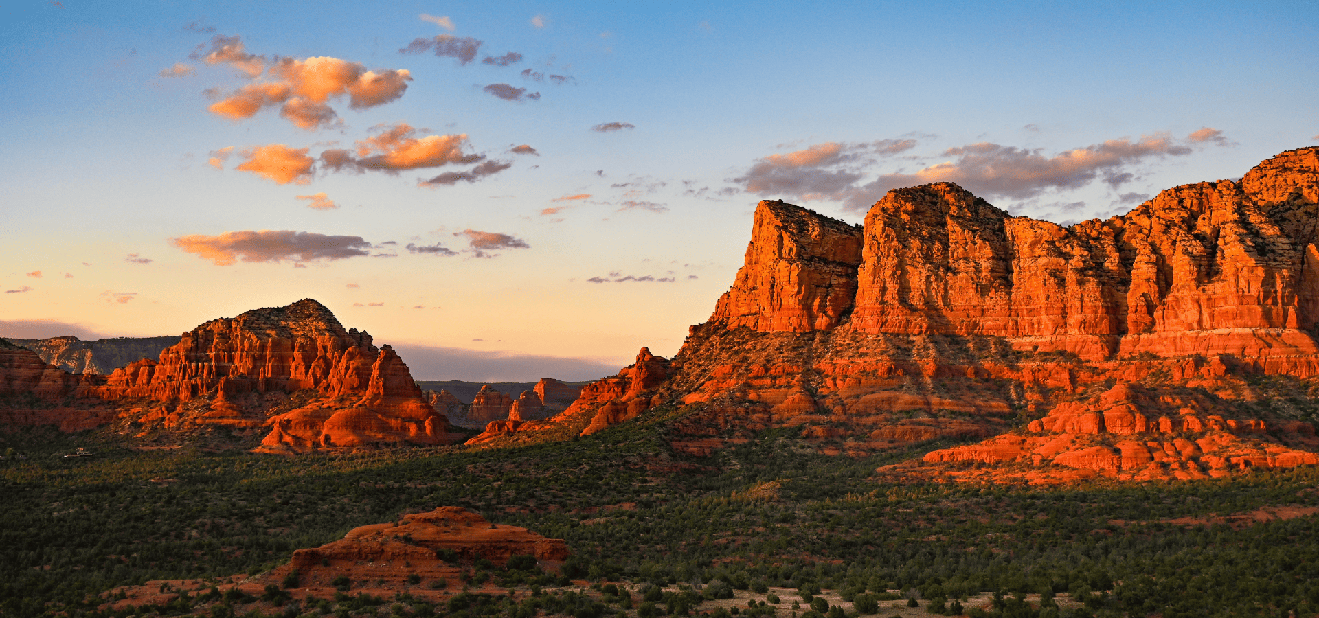 Sunset lights towering red sandstone cliffs and mesas in a desert canyon with orange-hued rock.